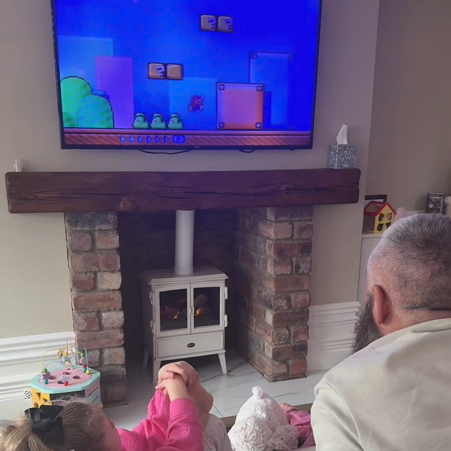 An adult and child playing a retro game together by the fireplace