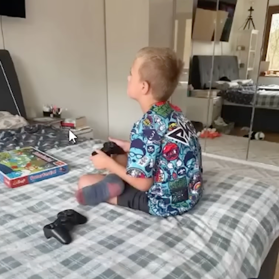 A child holding a controller and playing a retro game on a bedroom TV